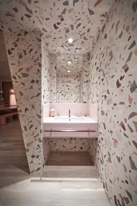 Modern minimalist bathroom with a patterned terrazzo floor and pink sink.