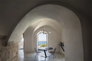 A modern interior with concrete walls and metal accents, featuring a round table and chairs.