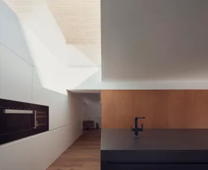 Modern kitchen space featuring white wooden cabinets on a matte black countertop, with natural light streaming through a larg
