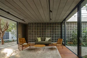 A modern living room featuring concrete walls, wood flooring, and a comfortable seating area.
