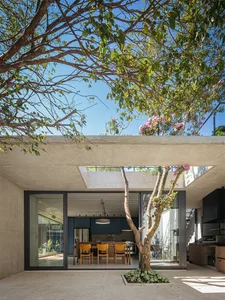 A modern minimalist kitchen with a concrete finish and large windows.