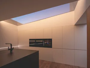 Modern kitchen featuring minimalist design with white cabinets, wood flooring, and a glass skylight.
