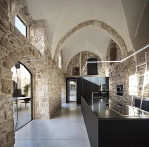 Modern residential kitchen with stone walls and concrete floor.