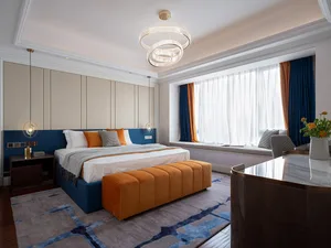 Contemporary bedroom design featuring a large bed, orange headboard, blue and orange curtains, and a circular chandelier.