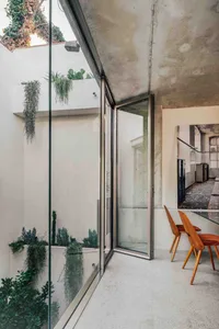 Modern industrial interior featuring concrete walls and glass doors with green plants.