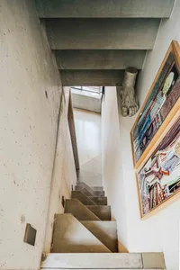 Concrete stairs leading up to a modern interior space with a concrete wall and a framed picture on the wall.