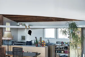 Modern kitchen with wooden shelves and glass countertops displaying assorted ingredients and containers, featuring a white wa