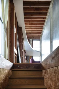 A modern industrial staircase with wooden steps and a white curved railing.