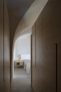 A minimalist bedroom with curved walls, white palette, and wooden furniture.