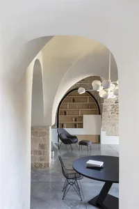 A modern living room with concrete and stone accents, featuring minimalist furniture and a circular table.