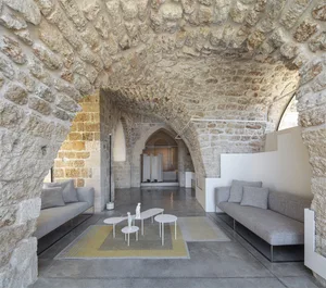 Modern lounge area with concrete floor, fabric seating, and stone arches