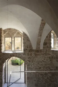 An interior space featuring medieval sandstone walls and a modern glass staircase.