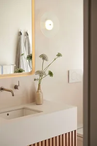 A minimalist bathroom with concrete and ceramic fixtures and a vase of flowers.