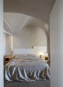 Minimalist bedroom with a concrete floor, bed, and twin bedside tables.
