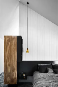 A modern minimalist bedroom with a wooden headboard and pendant light hanging from the ceiling.