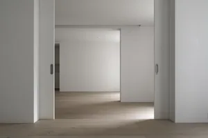 A minimalist interior design with light wood flooring and walls.