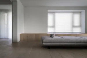 A minimalist living room featuring wood furniture and light-colored fabric.
