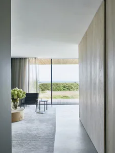 A minimalist residential interior featuring concrete, wood, and glass materials.