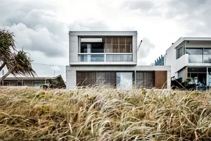 A two-story residential house with a modern design, constructed primarily of concrete, featuring large glass windows and a co
