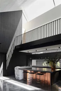 A modern kitchen featuring a copper-colored central island with black seating stools and a minimalist black wall.