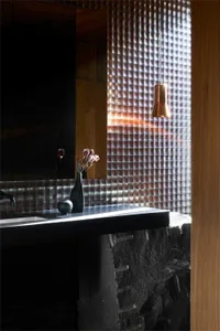 A sleek, minimalist bathroom with metallic tiles and wooden accents.