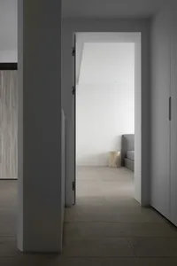 Modern minimalist bedroom with white walls and wooden floor.