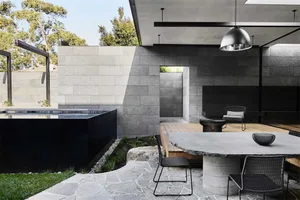 Modern outdoor dining area featuring concrete and metal elements, with a poolside setting.