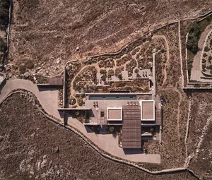 A modern residential building with a clay tile roof and an outdoor pool surrounded by desert landscape.