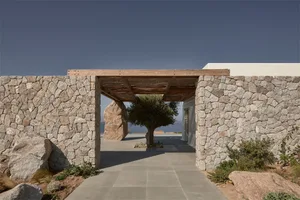 A modern stone entranceway with a tree in the middle.