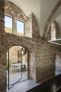 Historic architecture featuring stone walls and a glass door with a modern furniture setup.