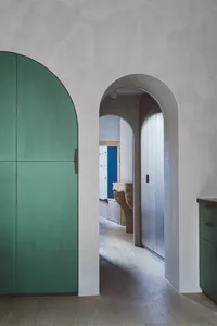 A minimalist interior design featuring green cabinets and wooden flooring.