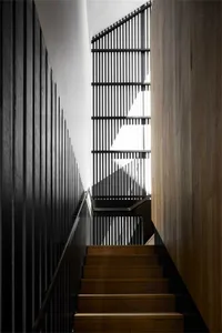 Interior staircase with wooden steps and railings, showcasing modern architectural design.