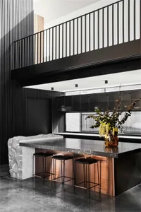 Modern kitchen bar featuring black granite counter and black stools with copper detailing.