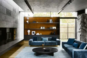 Modern living room featuring a concrete fireplace, blue sofas, and a wooden coffee table.