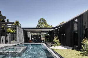 Modern minimalist house featuring concrete, black stone, and glass materials