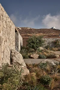 A modern residential exterior featuring a stone wall with a wooden beam.