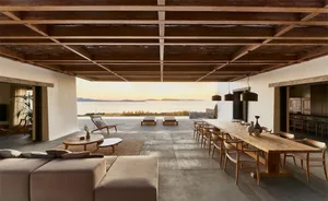 Contemporary residential living room featuring wooden furniture and concrete flooring with a view of the sunset.