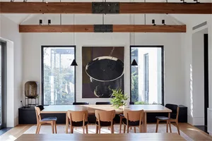 Modern dining room featuring wood table, metal chairs, glass pendant lights and minimalist black and white art
