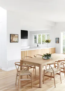Modern kitchen with a wooden dining table and chairs, white countertop, and large windows.