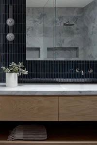 Modern bathroom with marble tiles and floating wooden vanity.