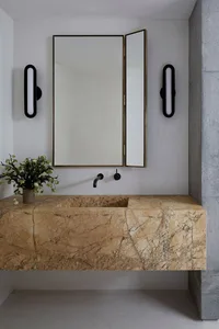 A minimalist bathroom featuring a marble sink with black fixtures, a mirror, and wall-mounted lights.