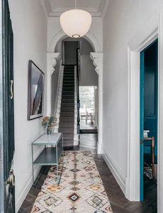 An entrance hall featuring a hardwood floor, a geometric rug, and a modern design aesthetic.