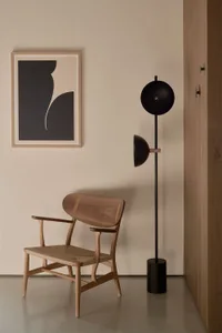 A minimalist living room with a wooden armchair and a black floor lamp.