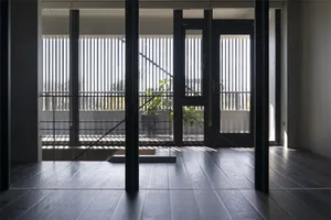 Modern living room featuring hardwood flooring and large windows with vertical blinds.