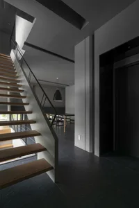 Modern entrance area with wooden stairs, concrete floor, and metal railing.