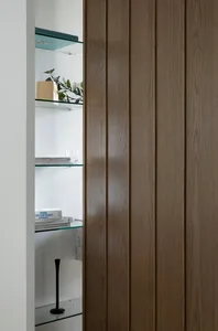Minimalist interior design featuring glass and wooden shelves with books and a plant.