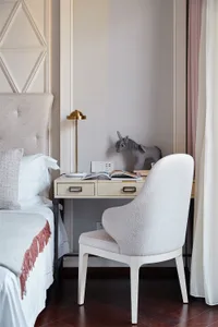 A minimalist office desk space featuring a wooden desk with a brass lamp, a unicorn plush toy, and an open book, alongside a 