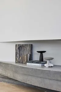 A minimalist shelf made of concrete with decorative objects on it.