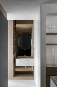 Modern minimalist bathroom featuring a white marble countertop with a circular mirror above it.