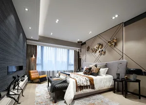 Modern bedroom with textured wall coverings, a gray upholstered bed, and a lounge chair in warm tones.